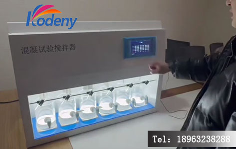 实验人员手持移液管,在搅拌器启动瞬间向烧杯中加入混凝剂,背景可见搅拌器数字屏上的转速参数。