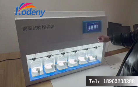 化验员正在清澈的原水样本前记录LDN-6M运行数据，面带轻松